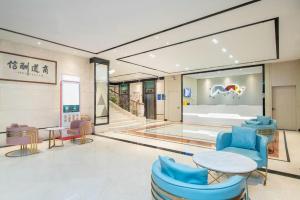 a lobby with blue chairs and a table in a building at Borrman Hotel Dongguan Houjie Wanda Plaza Liaoxia Metro Station in Dongguan