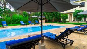 a pool with blue lounge chairs and an umbrella at Sunset Retreat Hotel in Arusha