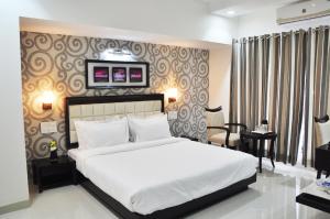 a bedroom with a large white bed and a desk at Hotel Krishna Inn, Aurangabad in Aurangabad
