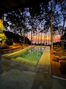 a swimming pool with a sunset in the background at Drifters Anchor in Ban Map Khangkhao