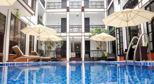 a large swimming pool with umbrellas in a building at Vinh Hung 2 City Hotel in Hoi An