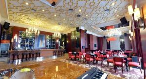 un ristorante con un bar con sedie rosse e un pianoforte di Babylon Hotel a Dongguan