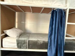 een stapelbed met een blauw gordijn in een stapelbedkamer bij Aura Hostel in Bangkok
