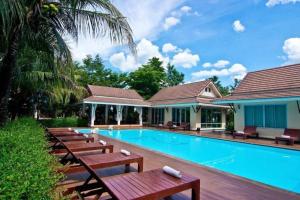 uma piscina com bancos ao lado de uma casa em The Forest Home Resort em Ban Dong