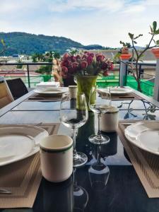 een tafel met borden en glazen en een vaas met bloemen bij Kata Lina rooftop in Kata Beach