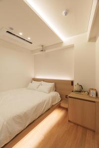a bedroom with a white bed and a wooden floor at 이루다스테이 호텔 고척돔점 in Seoul