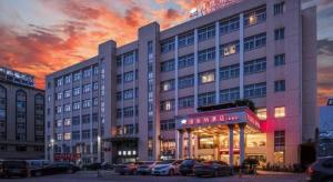 un grande edificio con auto parcheggiate in un parcheggio di Vienna Hotel Hangzhou Binkang Road Metro Station a Hangzhou