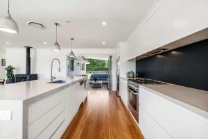 a kitchen with white cabinets and a black wall at Forresters Lodge by Coast Hosting in Wamberal North