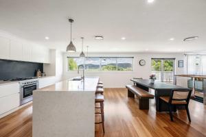 a kitchen with white cabinets and a table and chairs at Forresters Lodge by Coast Hosting in Wamberal North +22 photos