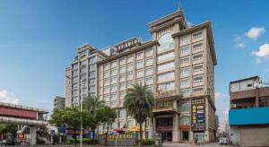 a large white building with palm trees in front of it at Fu Yuan Hotel in Dongguan