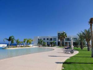 a resort swimming pool with palm trees and a building at Apartment Maldives in Khóti Nisí