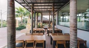 una sala con tavoli, sedie e palme di At One Hotel Chiangrai a Ban San Ton Kok