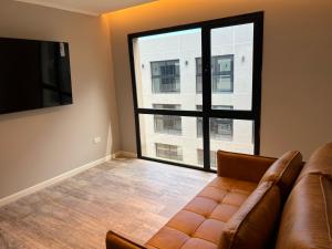 a living room with a couch and a large window at Nogales Apartamentos in Mar del Plata