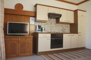 a kitchen with white cabinets and a tv and a stove at Ferienwohnungen Gudrun Bernhard in Berg im Drautal