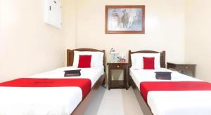 two beds in a room with red and white sheets at Dino Residences in Daro