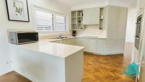 a kitchen with white cabinets and a counter top at Village Bay Lake house family Lake House with Spa in Marks Point