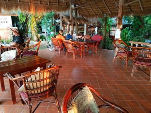 a patio with tables and chairs and people sitting at tables at Mut Mee Garden Guest House in Nong Khai