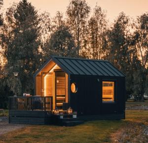 a black tiny house sitting on top of a field at Arctic circle cabin 2 in Rovaniemi +8 photos
