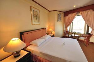 una camera da letto con un grande letto con una lampada e un tavolo di Royal Diamond Hotel a Phetchaburi Altre 48 foto