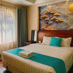 a bedroom with a large bed with a painting on the wall at Hanoi Cozy Boutique Hotel in Hanoi