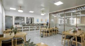 Un restaurante con mesas y sillas en una sala. en GreenTree Inn Zhangjiagang Yangshe Old Street Stadium, en Zhangjiagang