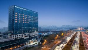a tall glass building next to a street with traffic at Mercure Chengdu Longtan in Chengdu