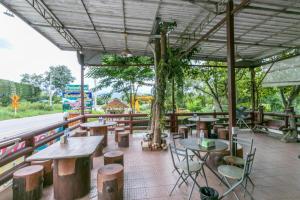 un ristorante con tavoli e sedie in legno e alberi di OYO 75317 Pintara Fahsai Resort a Ban Khan Takhian