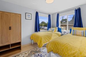 two beds in a bedroom with blue curtains and a window at Seaside Getaway B in Seaside