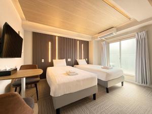 a hotel room with two beds and a desk at Osaka Ebisu Hotel in Osaka