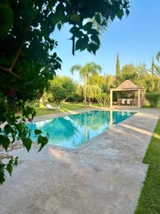 basen na podwórku z altaną w obiekcie Luxueuse villa avec piscine et magnifique jardin w mieście Gzoula