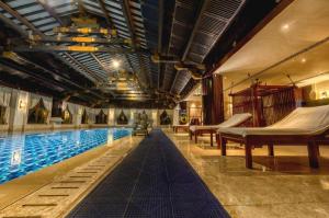 a swimming pool with tables and hammocks in a building at Tong Que Tai Jinling Hotel Tongling Anhui in Tongling