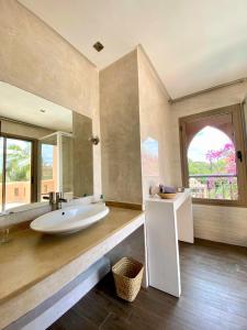 duża łazienka z dużą wanną i dużym lustrem w obiekcie Luxueuse villa avec piscine et magnifique jardin w mieście Gzoula