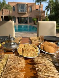 stół z jedzeniem i chlebem na nim i basenem w obiekcie Luxueuse villa avec piscine et magnifique jardin w mieście Gzoula