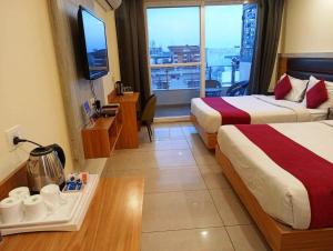 a hotel room with two beds and a large window at MLS Prime Inn - Near Dehradun Railway Station in Dehradun