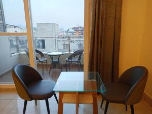 a glass table and chairs in a room with a window at MLS Prime Inn - Near Dehradun Railway Station in Dehradun