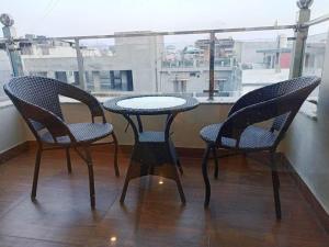 three chairs and a table on a balcony with a window at MLS Prime Inn - Near Dehradun Railway Station in Dehradun
