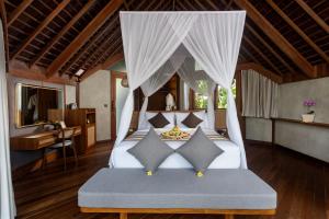 a bedroom with a bed with a canopy at The Pulu Villas by GenuineHost in Ubud