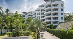 um grande edifício branco com uma palmeira em frente em Sansuri Resort em Praia de Surin