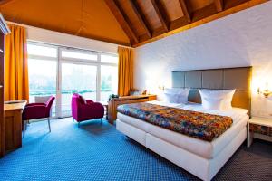 Un dormitorio con una cama grande, un escritorio y sillas. en Hotel Reiterhof, en Wirsberg 33 fotos más