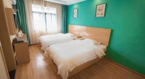 2 camas en una habitación con una pared verde en Shell Hefei Luyang District Sipai Building Subway Station Hotel, en Hefei