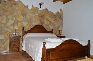 a bedroom with a bed and a stone wall at Casas Rurales Carrizosa in Navaconcejo