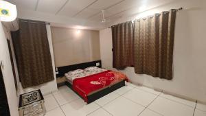 a small bedroom with a red bed and curtains at Heaven Accommodations in Rajkot