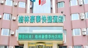 un edificio rosa con scritte in cinese sopra di GreenTree Inn Qingdao Licang Shuyan Road Daweng Square Express Hotel a Laoshan