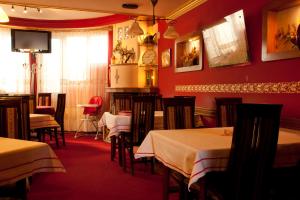 une salle à manger avec des tables, des chaises et des murs rouges dans l'établissement Taxi Bar Motel, à Gradiška