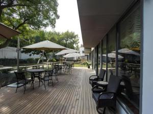 eine Außenterrasse mit Tischen, Stühlen und Sonnenschirmen in der Unterkunft Jinjiang Metropolo Shanghai Minhang in Shanghai