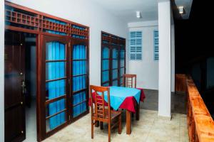 阿鲁特伽马Hotel Blue Sapphire的餐厅里有一张桌子、几扇门、一张桌子和几把椅子。