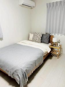 een bed in een witte kamer met een raam bij 馥の森 in Kumamoto