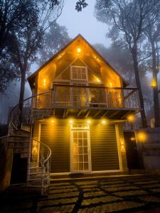 een huis met een veranda en een balkon in de nacht bij Kings Holidays Munnar in Ūdumbanshola