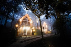 een houten huis 's nachts met lichten aan bij Kings Holidays Munnar in Ūdumbanshola