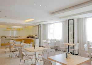 una sala da pranzo con tavoli e sedie bianche di City Comfort Inn Nanning Normal University Changgang Road Metro Station a Nanning